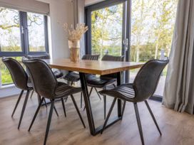 A dining table with chairs and a vase at Isca Lodge in Wombleton
