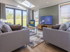 A living room with a sofa and television at Isca Lodge in Wombleton
