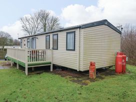 A caravan with decking and gas cylinders at Caravan number 77
