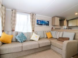 A living room with a sofa and cushions at Caravan number 77