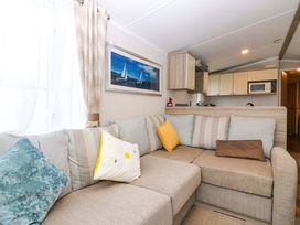 A living room with a sofa and kitchen area at Caravan number 77