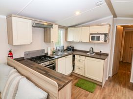 A kitchen with a sink, cooker, and microwave at Caravan number 77