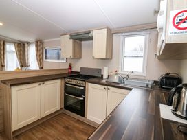A kitchen with cabinetry, sink, and appliances at Caravan number 77
