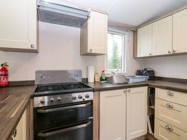 A kitchen with cabinets, gas stove, and sink at Caravan number 77