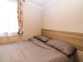 A bedroom with a bed and curtains at Caravan number 77