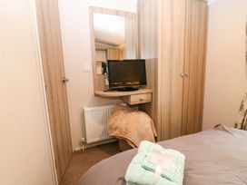 A bedroom with a television and mirror at Caravan number 77