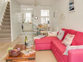 A living room with a sofa, coffee table, and dining area at Seahorse Cottage in Weymouth