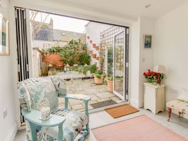 A living room with an armchair and sliding doors leading to a garden at Seahorse Cottage in Weymouth