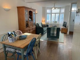 A dining area with a table and chairs beside a living area with a sofa and television at Seahorse Cottage in Weymouth