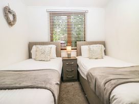 A bedroom with two beds and a nightstand at Terabitha Lodge in Troutbeck