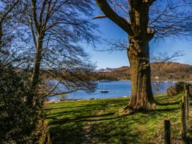 A view of a lake with a boat, trees, and a pathway at Terabitha Lodge in Troutbeck