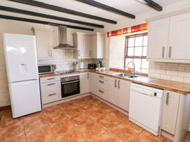 A kitchen with a refrigerator, oven, sink, and cabinets at Ty Fferm Newport