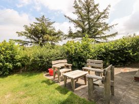 A garden with wooden chairs and table at Ty Fferm in Newport