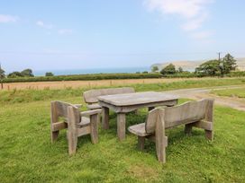 A table and benches overlooking a field and the ocean at Ty Fferm in Newport