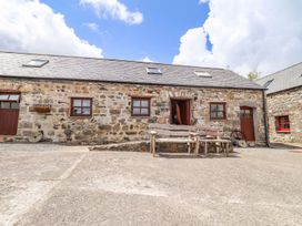 A stone building with wooden benches in an outdoor area at Ty Felin Newport