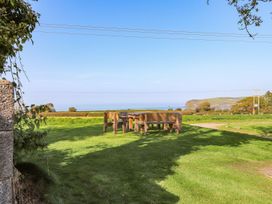 An outdoor seating area with a table and chairs overlooking the ocean at Ty Felin Newport