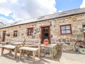 An outdoor area with wooden chairs and stone wall at Ty Felin Newport