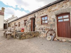 An outdoor area with stone building and wooden chairs at Ty Felin Newport