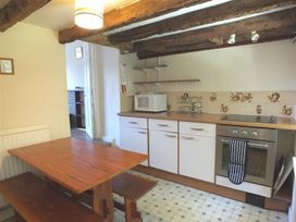 A kitchen with a table and benches with appliances at Dinas Island Cottage in Dinas Cross