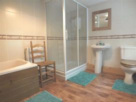 A bathroom with a bathtub shower and sink at Dinas Island Cottage in Dinas Cross