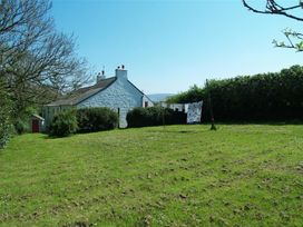 A house with a clothesline and grass at Dinas Island Cottage in Dinas Cross