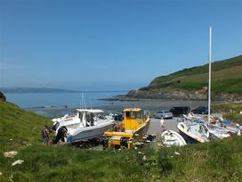 A beach scene with boats and people at Dinas Island Cottage Dinas Cross