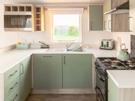 A kitchen with a sink, gas stove, and microwave at Morwenna in Hayle