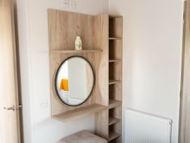 A wooden shelf with a mirror and vase at Morwenna in Hayle