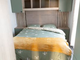 A bedroom with a bed and shelves at Lamorna in Hayle
