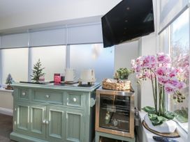A kitchen with a cabinet and flowers at The Summerhouse in Llandudno
