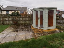A shed on a paved area with grass at Braeburn in Bamburgh