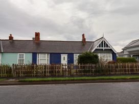 A house with a blue and green exterior and a picket fence at Braeburn in Bamburgh