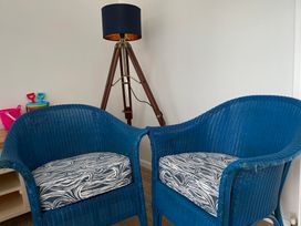 Two blue chairs and a tripod lamp in a living room at Braeburn in Bamburgh