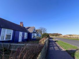 A purple house with a fence and road at Braeburn in Bamburgh