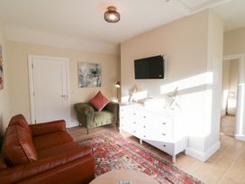 A living room with a sofa, armchair, and television at Duck Cottage