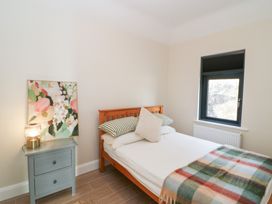 A bedroom with a bed, nightstand, and window at Duck Cottage