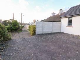 A driveway with a concrete fence and houses in the background at Duck Cottage