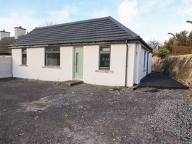 A bungalow with a green front door and gravel driveway at Duck Cottage
