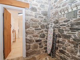 A utility room with an ironing board and hooks at Dairy Cottage Bullhornstone near South Brent
