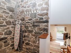 A hallway with a stone wall and an ironing board at Dairy Cottage in Bullhornstone near South Brent