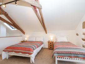 A bedroom with two beds and bedside tables at Dairy Cottage Bullhornstone near South Brent