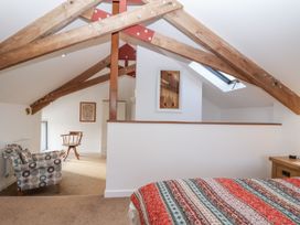 A bedroom with a bed and a chair at Dairy Cottage in Bullhornstone near South Brent