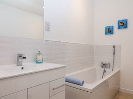 A bathroom with a sink, bath, and mirror at Dairy Cottage in Bullhornstone near South Brent