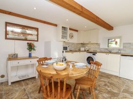 A kitchen with a round table and chairs at Swallow Cottage in Bullhornstone near South Brent
