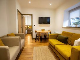 A living room with a sofa, armchairs, table and television at Aspen Apartment in Llanrwst