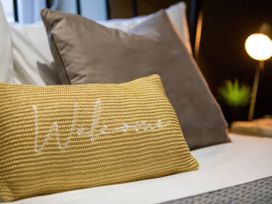 A bed with pillows and a lamp at White Willow Apartment in Llanrwst