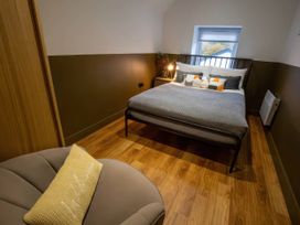 A bedroom with a bed and chair at White Willow Apartment in Llanrwst