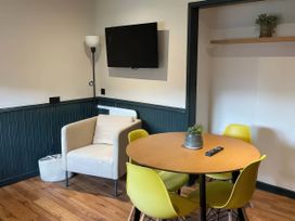 A dining room with a table and yellow chairs at Ash Cottages Llanrwst
