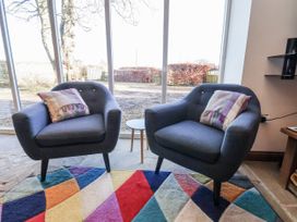 Two armchairs with cushions and a table in a living room at Chestnut Barn Aislaby near Whitby