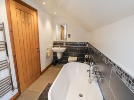 A bathroom with a bathtub, toilet, sink, and mirror at Chestnut Barn Aislaby near Whitby